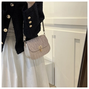Detail of beige pleated shoulder bag with gold clasp shown on a fashion model