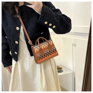 Close-up of geometric woven crossbody bag with brown PU trim on a mirror selfie