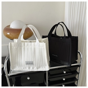 Close-up of quilted cotton tote bags in black and cream white with fashion bag label