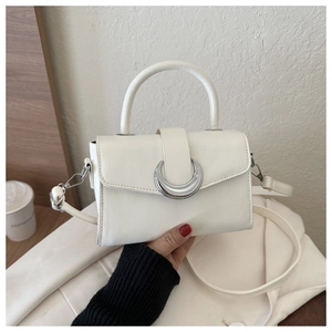 Detail of white leather crossbody bag with silver crescent buckle on white jacket