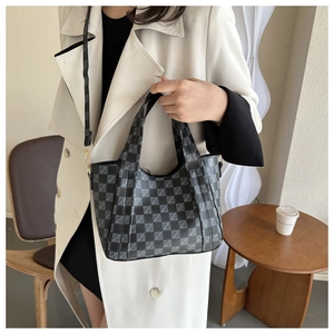 Detail of checkered bucket bag featuring reinforced handles and gold-tone hardware accents