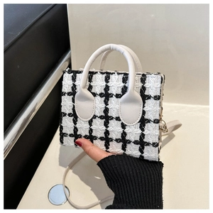 Detail of classic black and white tweed texture and white leather strap on mini handbag
