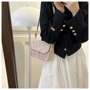 Detail view of pink pleated saddle bag with a golden horseshoe buckle on a model