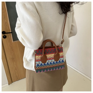 Detailed view of colorful woven ethnic handbag with brown leather strap and sturdy handles