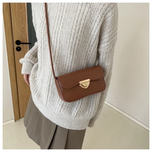 Close-up of a brown vintage leather shoulder bag with a gold triangle metal buckle