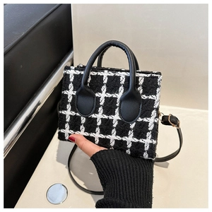 Macro detail of black and white tweed fabric texture with leather handles on a handbag
