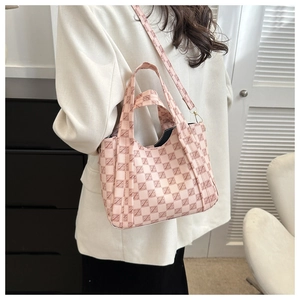 Side view of pink checkered tote bag on a model wearing white blazer and black dress