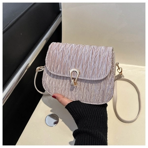 Detail of champagne pleated crossbody bag featuring a golden horseshoe metallic clasp