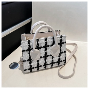 Detail of black and white tweed mini bag showing fabric texture and white leather handle