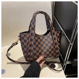 Close-up of vintage checkered pattern with monogram detail and adjustable shoulder strap