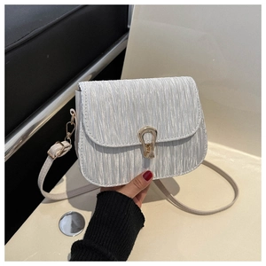 Detail of silver pleated crossbody bag featuring a golden horseshoe metallic buckle clasp
