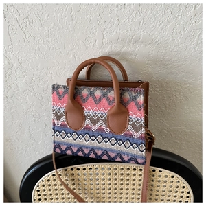 Detailed macro view of woven bohemian crossbody bag with geometric patterns on a wicker chair