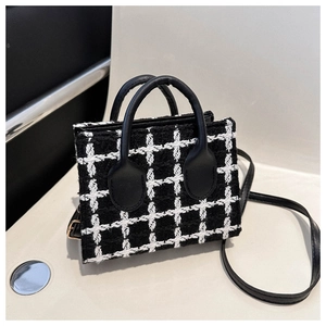 Detail shot of black and white checkered tweed handbag with elegant rounded top handles