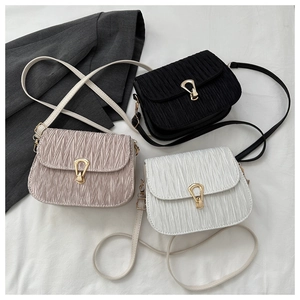 Three pleated crossbody bags in black, pink, and white with gold horseshoe buckles