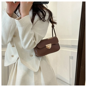 Detail of dark brown vintage underarm bag with gold triangular buckle and knot strap
