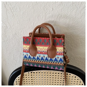 Close-up of colorful geometric woven pattern and brown faux leather handle on square bag