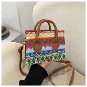 Close-up of Bohemian geometric pattern woven handbag with brown leather strap and gold buckle