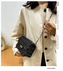 Detail of black tweed crossbody bag with golden chain strap and metallic clasp