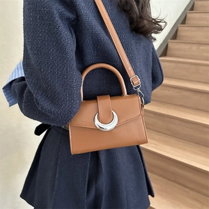 Brown retro small square crossbody bag featuring a silver crescent moon buckle on a model