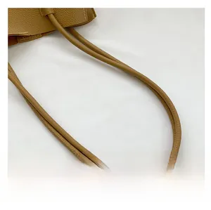 Close-up of caramel brown lychee leather handles with detailed stitching on a felt bag