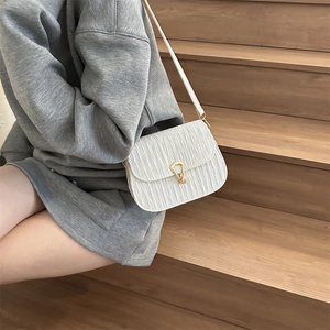 White ruched crossbody bag with gold horseshoe lock shown in a casual lifestyle setting