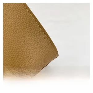 Close-up of brown litchi grain leather showing detailed cream white stitching craft