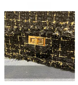 Detailed view of the gold metal twist lock on black tweed plaid crossbody bag