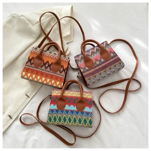 Three Bohemian woven crossbody bags with ethnic patterns and leather straps on white fabric