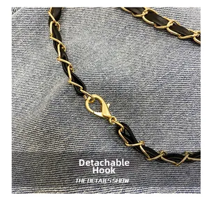 Detail of detachable gold chain strap with black leather weave and metal lobster hook