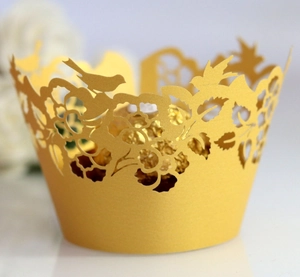 Elegant gold laser-cut cupcake wrappers with floral bird patterns for event decoration