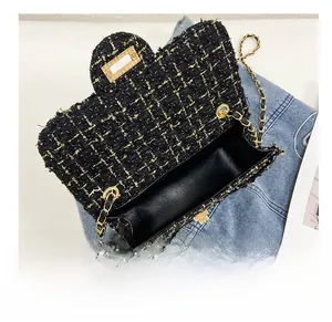 Detail view of the black tweed crossbody bag interior with gold chain and metal clasp