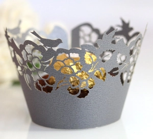 Detailed laser-cut cupcake wrapper with intricate floral and bird designs in silver gray