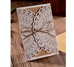 Close-up of laser-cut lace wedding invitation with kraft paper insert and hemp rope tie