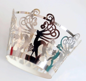 Macro detail of laser-cut silver muffin wrappers with festive reindeer and snowflake patterns