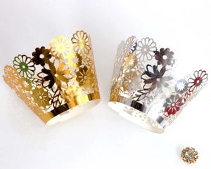 Detail of laser-cut flower patterns on gold and silver cupcake wrappers for party decor