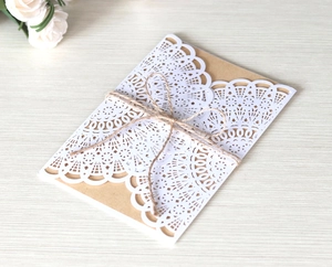 Detail of laser-cut hollow lace invitation with kraft paper card and natural jute twine