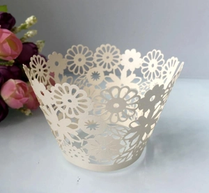 Close-up of laser-cut cream cupcake wrapper featuring intricate floral daisy patterns