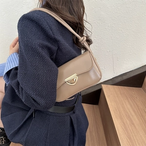 Vintage khaki underarm bag with gold triangle buckle and knotted strap on stairs