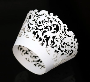 Detail of white laser-cut cupcake wrapper featuring intricate European vine lace patterns