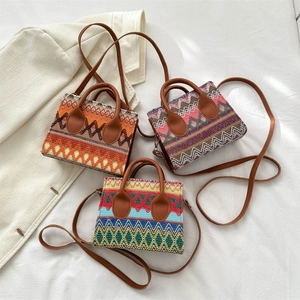 Ethnic bohemian woven crossbody bags with leather handles on white fabric background