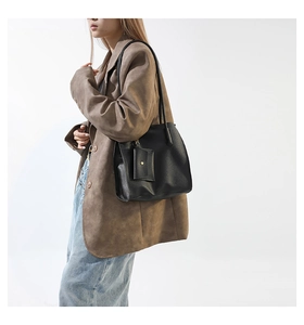 Detail view of black lychee-grain leather tote bag with a small square coin purse pendant