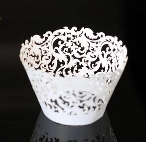 Macro detail of white laser-cut cupcake wrappers with elegant vine patterns