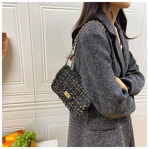 Detail shot of black tweed crossbody bag with gold chain strap and turn-lock closure