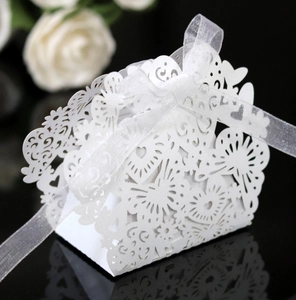 Detail of laser-cut white favor box with heart patterns and white organza ribbon