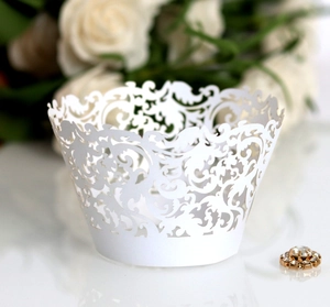 Detailed laser-cut vine patterns on a white paper cupcake wrapper for wedding decor