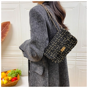 Detail of black tweed crossbody bag featuring gold chain strap and textured fringe edges