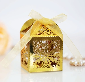 Close-up of golden laser-cut snowflake gift box with matching ribbon and pearl decor