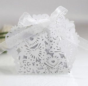 Macro view of white laser-cut butterfly candy box with heart motifs and organza ribbon