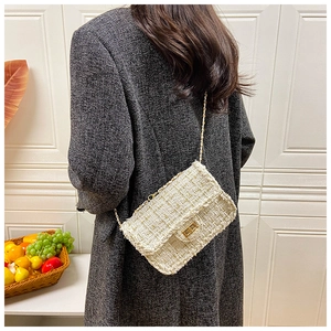 Detailed view of tweed crossbody bag with gold chain strap on a wool blazer