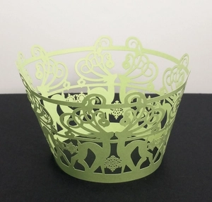 Close-up of laser-cut reindeer and snowflake hollow patterns on green cupcake wrappers